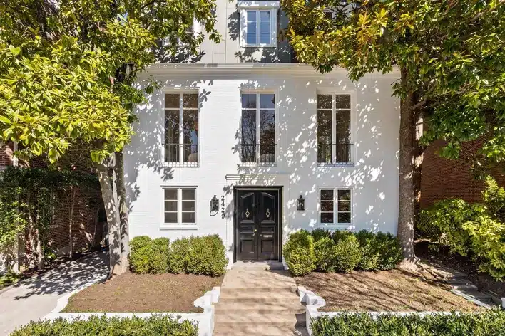 Elegant white brick building with black double doors and symmetrical windows, representing a classic structure suited for Embassy Property Conversion.
