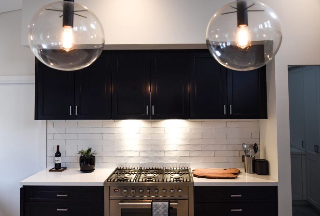 Modern kitchen with dark cabinetry and a white staggered tile backsplash, illustrating unique kitchen backsplash ideas.
