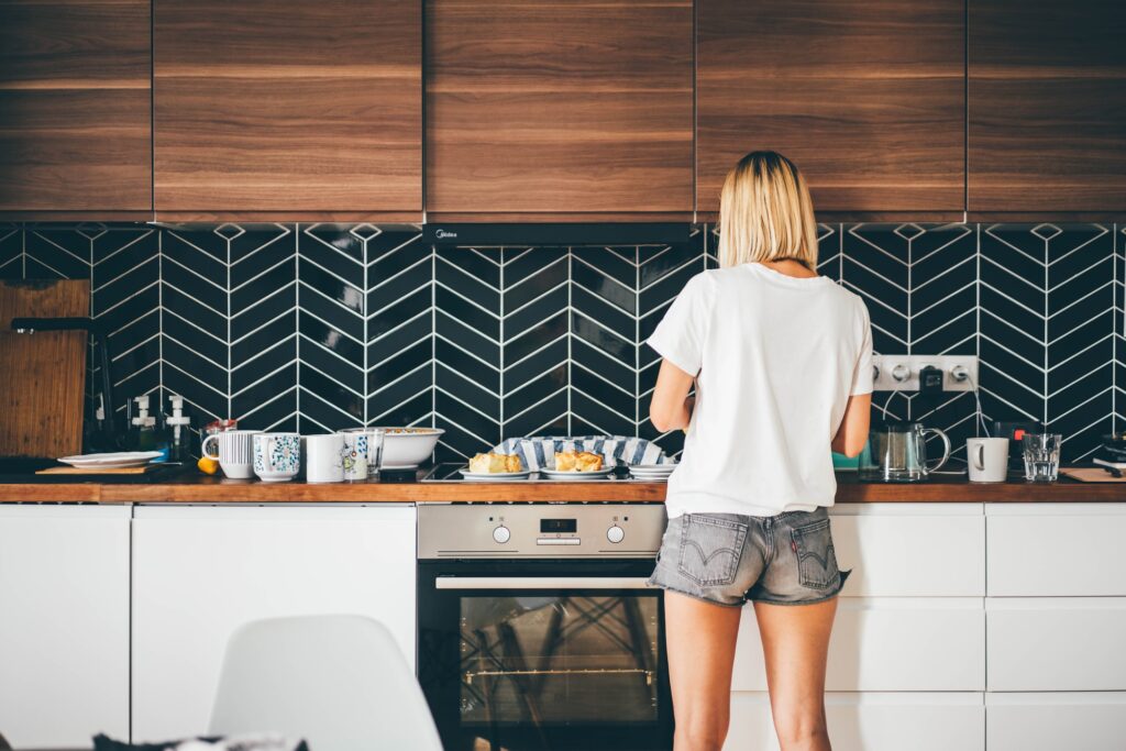 Woman standing in front of a kitchen counter with a bold black-and-white chevron tile backsplash, showcasing unique kitchen backsplash ideas.